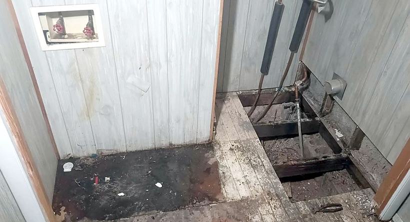 Before: a laundry room floor torn out to the joists, with rotted boards