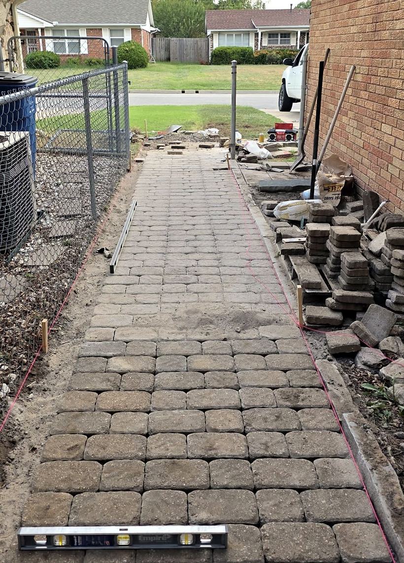 Pavers being laid on the base, with a level on the newest row