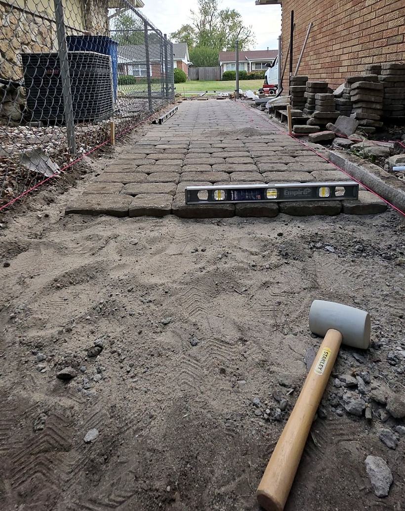 A level and a rubber mallet on the newest row of pavers